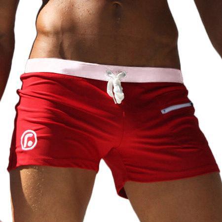 Close-up of athletic male torso wearing red swim trunks with white waistband and drawstring
