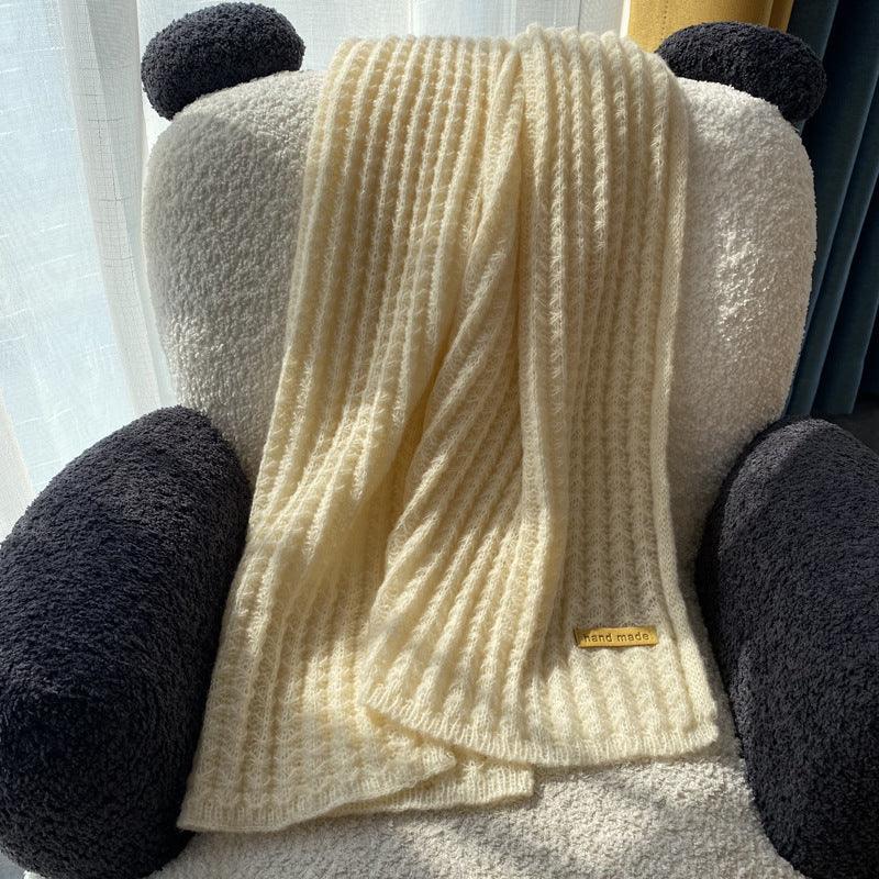 Cream knitted handmade scarf draped over cozy black and white panda bear armchair near window