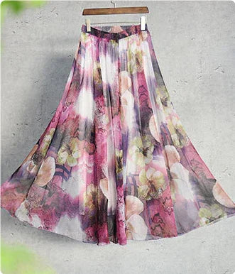 Flowy floral maxi skirt with pink, purple, and green hues hanging on wooden hanger against gray background