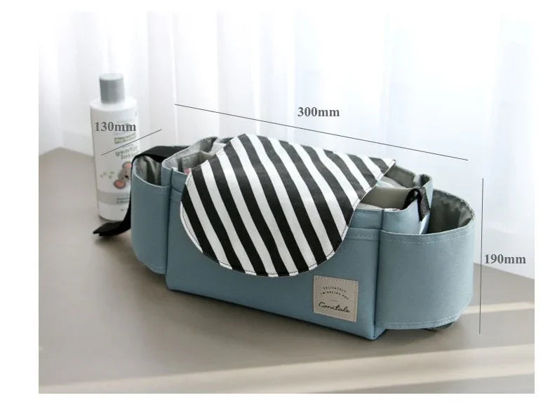 Blue storage organizer bag with striped black and white flap, measuring 300mm by 190mm by 130mm, beside a white bottle
