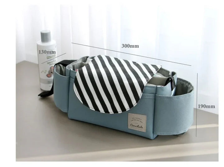 Blue storage organizer bag with striped black and white flap, measuring 300mm by 190mm by 130mm, beside a white bottle