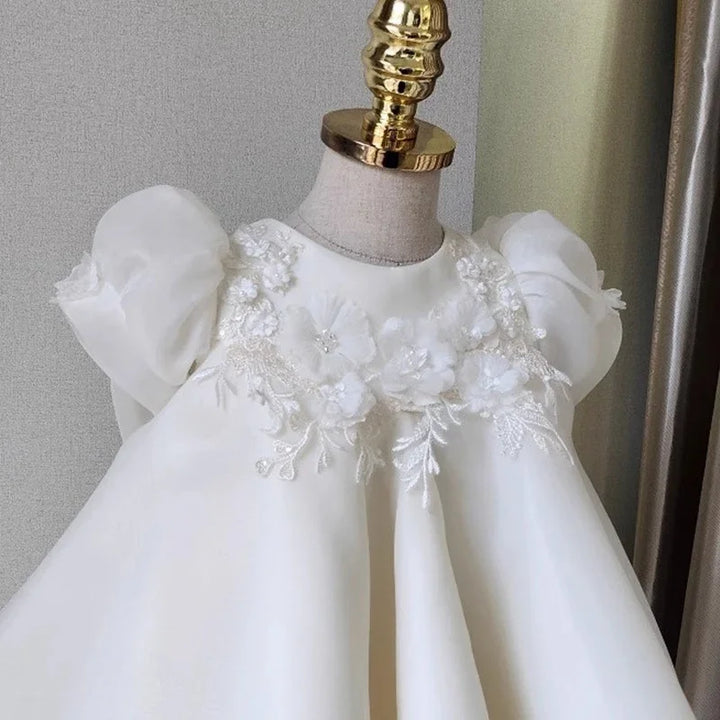 Elegant white baby dress with puff sleeves and floral embroidery on bodice displayed on mannequin