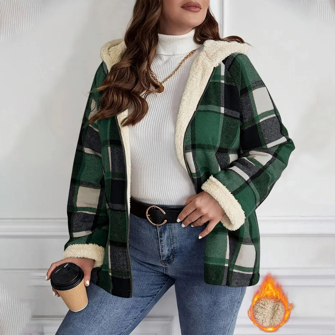 Woman wearing green plaid fleece lined jacket with hood, white turtleneck, blue jeans, holding coffee cup