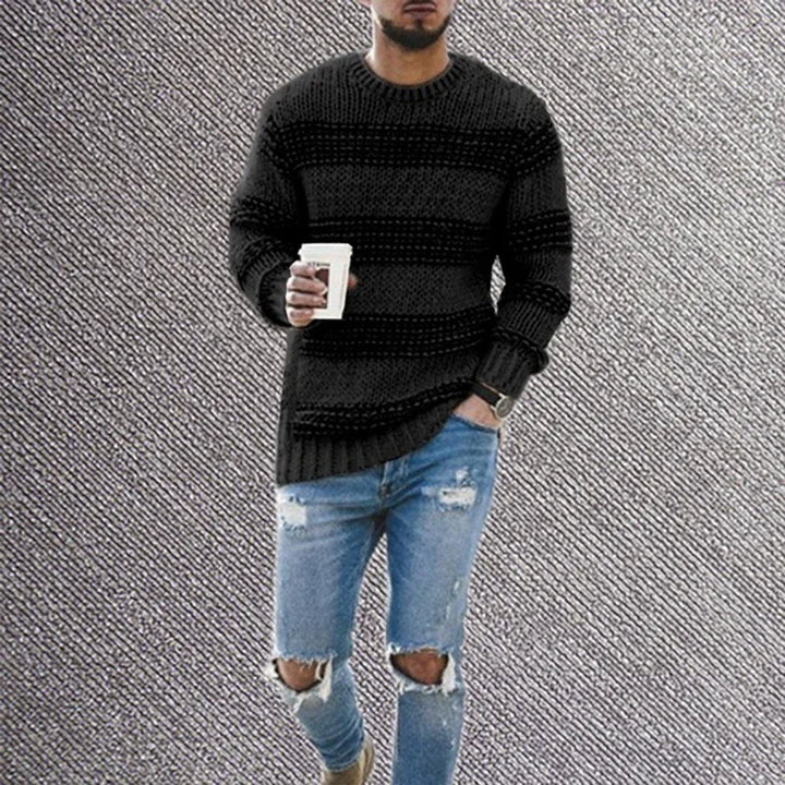 man wearing black knitted sweater and ripped skinny blue jeans holding coffee cup