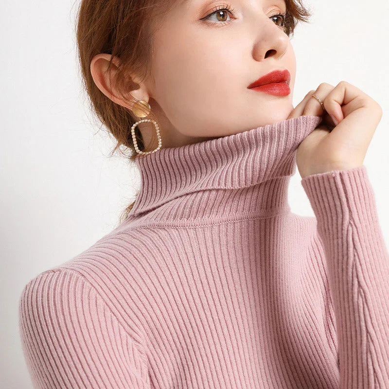 Woman wearing pink ribbed turtleneck sweater and statement gold and pearl square earrings with red lipstick