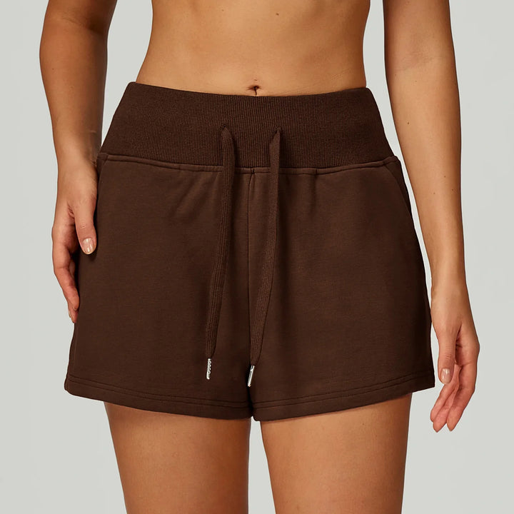 Close-up of a person wearing brown high-waisted drawstring shorts with ribbed waistband