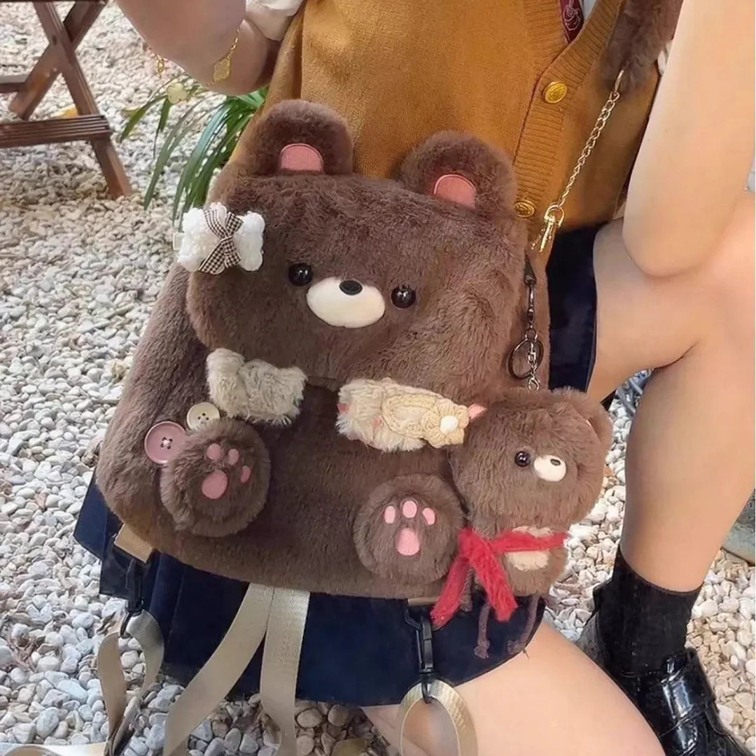 Brown fluffy teddy bear backpack with small bear keychain and decorative patches worn by person outdoors