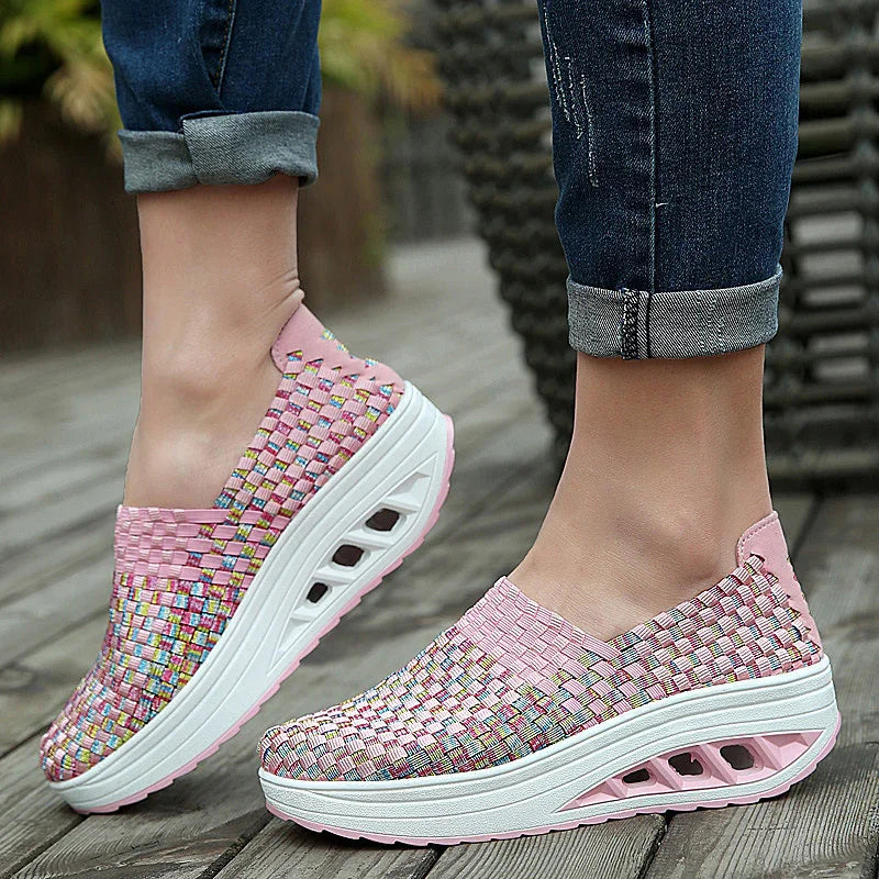 Stylish pink woven platform slip-on shoes worn with rolled-up denim jeans on wooden floor