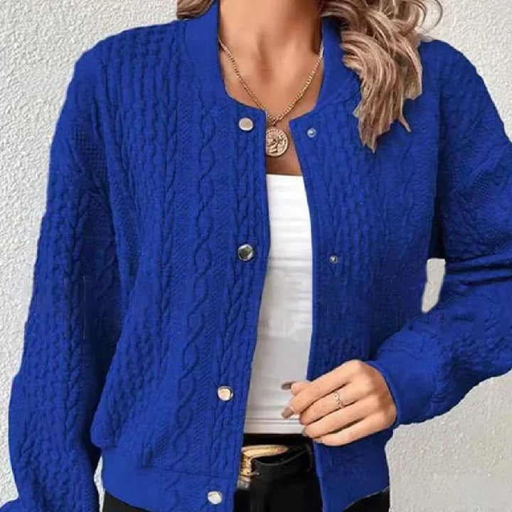 Woman wearing royal blue cable knit button-up cardigan over white top with gold necklace