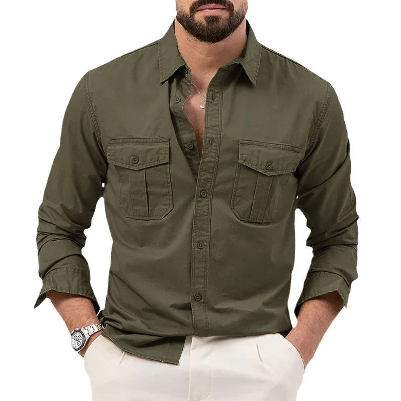 man wearing olive green button-up shirt with chest pockets and white pants, hands in pockets