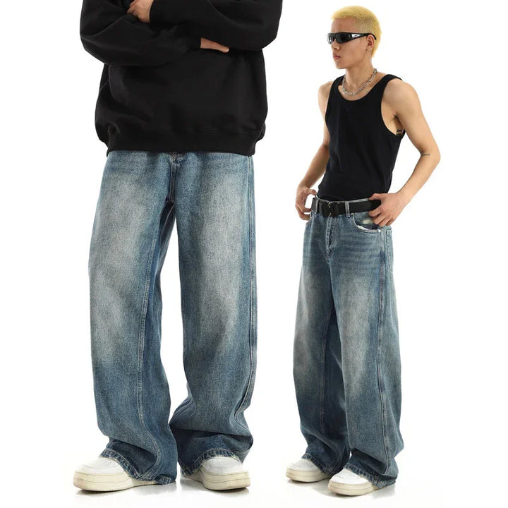 Two models wearing baggy faded blue jeans, one with black sweatshirt, other with black tank top and sunglasses
