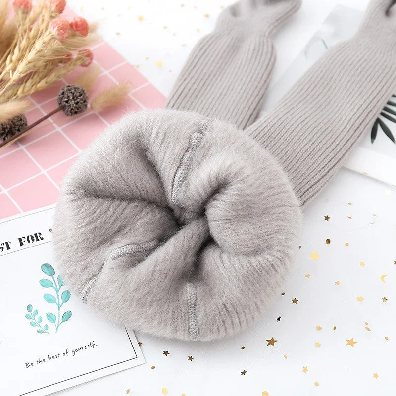 Soft grey fuzzy knit leg warmers with textured stitching on white background with dried flowers and decorative cards