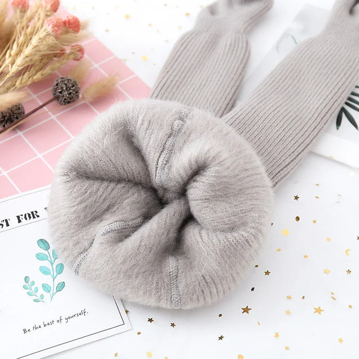 Soft grey fuzzy knit leg warmers with textured stitching on white background with dried flowers and decorative cards