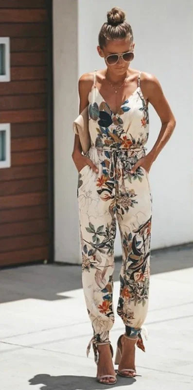 Woman wearing a white floral print sleeveless jumpsuit with ankle ties and sunglasses outdoors