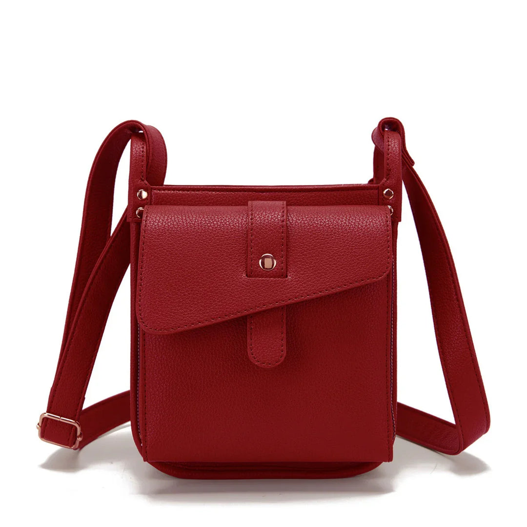 Red leather crossbody bag with adjustable strap and front flap pocket on white background