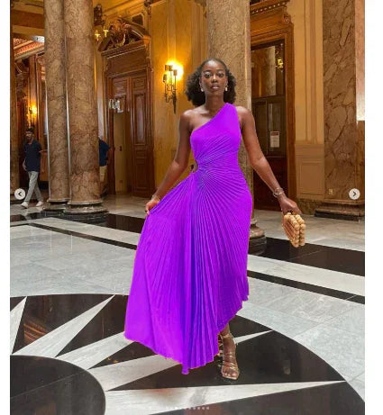 Elegant woman in vibrant purple one-shoulder pleated dress posing in luxurious marble hall