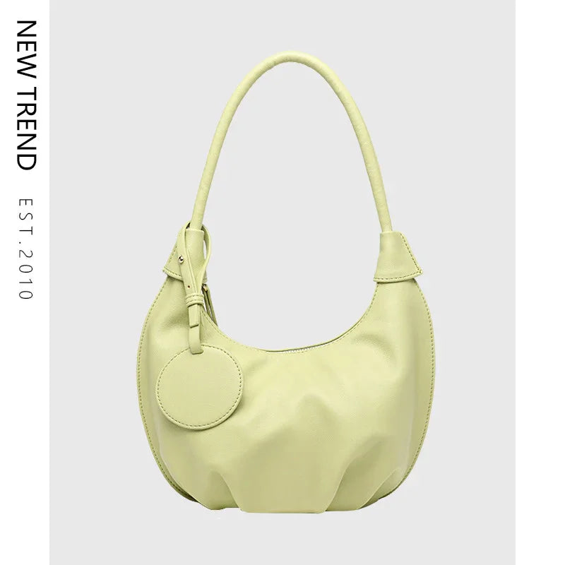 Light green leather shoulder hobo bag with round tag on gray background, new trend handbag
