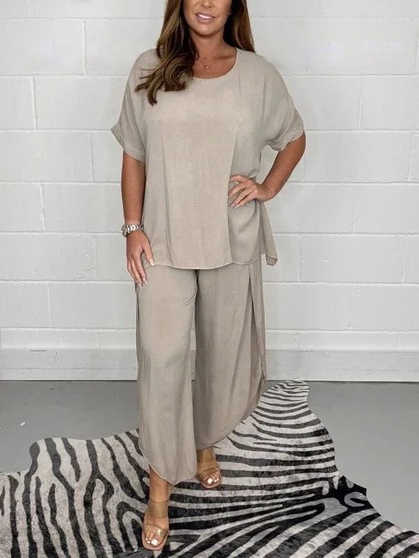 Woman wearing a loose beige lounge set with wide-leg pants and short sleeves, standing on zebra print rug