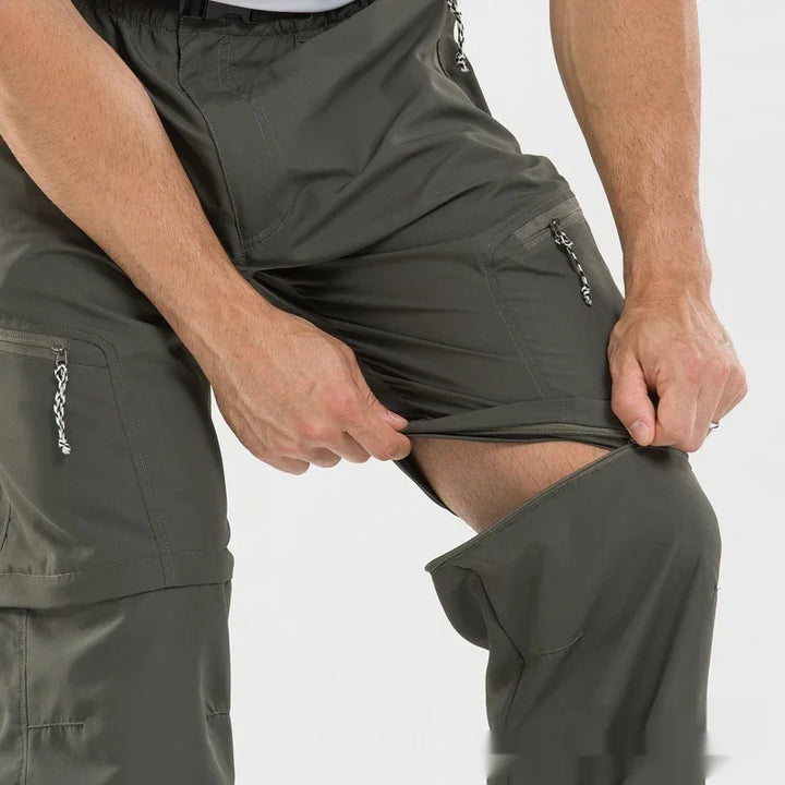 Man wearing olive green zip-off convertible hiking pants, showing detachable pant legs with zipper detail