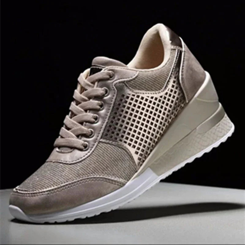 Stylish beige wedge sneaker with perforated side panels and white sole on gray surface