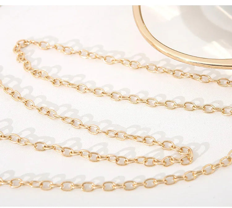 Close-up of delicate gold chain necklace with oval links on white background