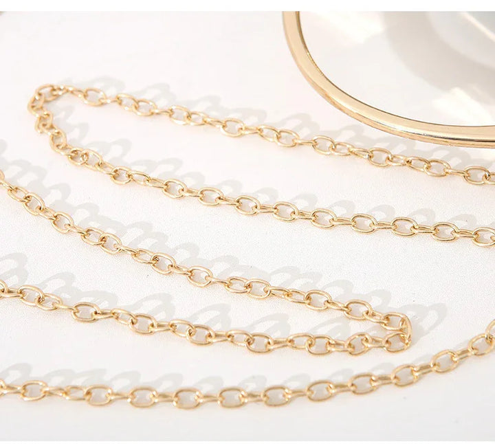 Close-up of delicate gold chain necklace with oval links on white background