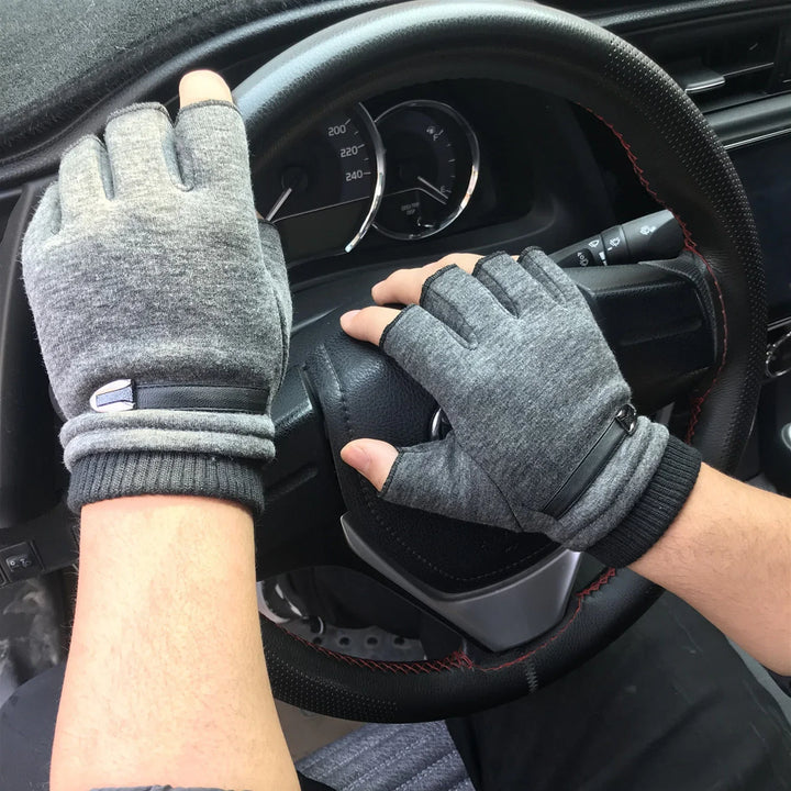Hands wearing gray fingerless driving gloves gripping a black leather steering wheel in a car