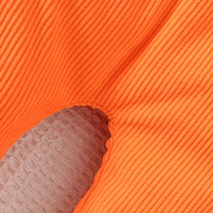 Close-up of bright orange ribbed knit fabric with textured beige background