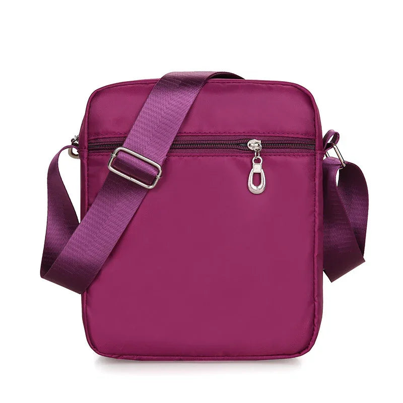 Compact purple crossbody bag with adjustable strap and front zipper pocket