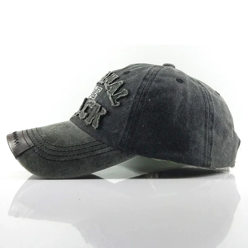 Black distressed baseball cap with embroidered text and leather patch on brim, studio white background