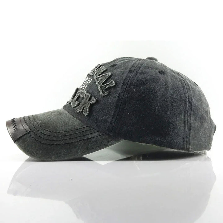 Black distressed baseball cap with embroidered text and leather patch on brim, studio white background