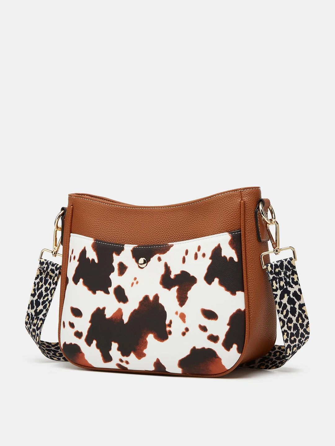 Brown leather handbag with white and black cow print front pocket and leopard print adjustable strap