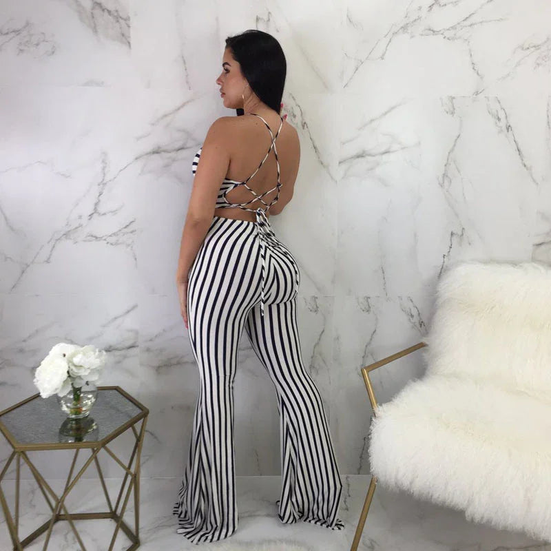 Woman wearing black and white striped backless halter top and matching bell-bottom pants in a modern marble room