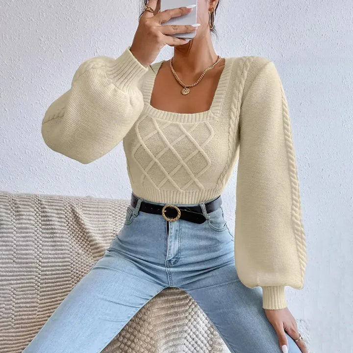 Woman wearing cream cable knit sweater with puff sleeves and light blue high-waisted jeans