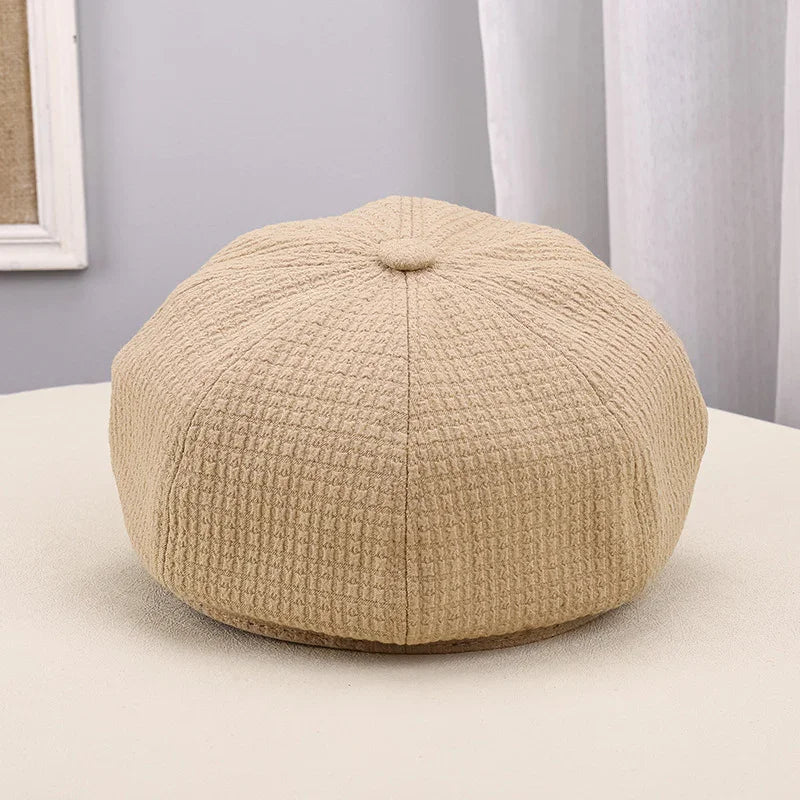 Beige textured wool beret hat on neutral surface with soft natural lighting