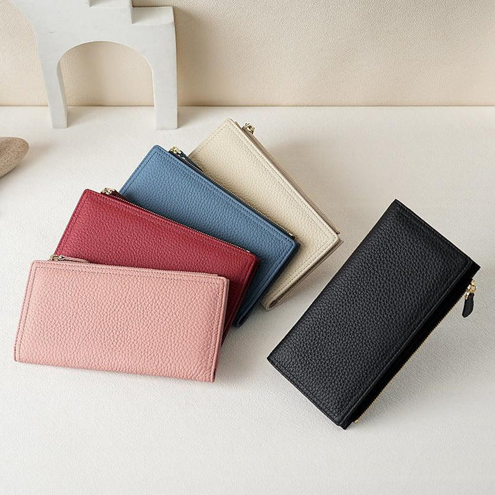 Set of textured leather wallets in pink, red, blue, beige, and black, with gold zipper on light surface