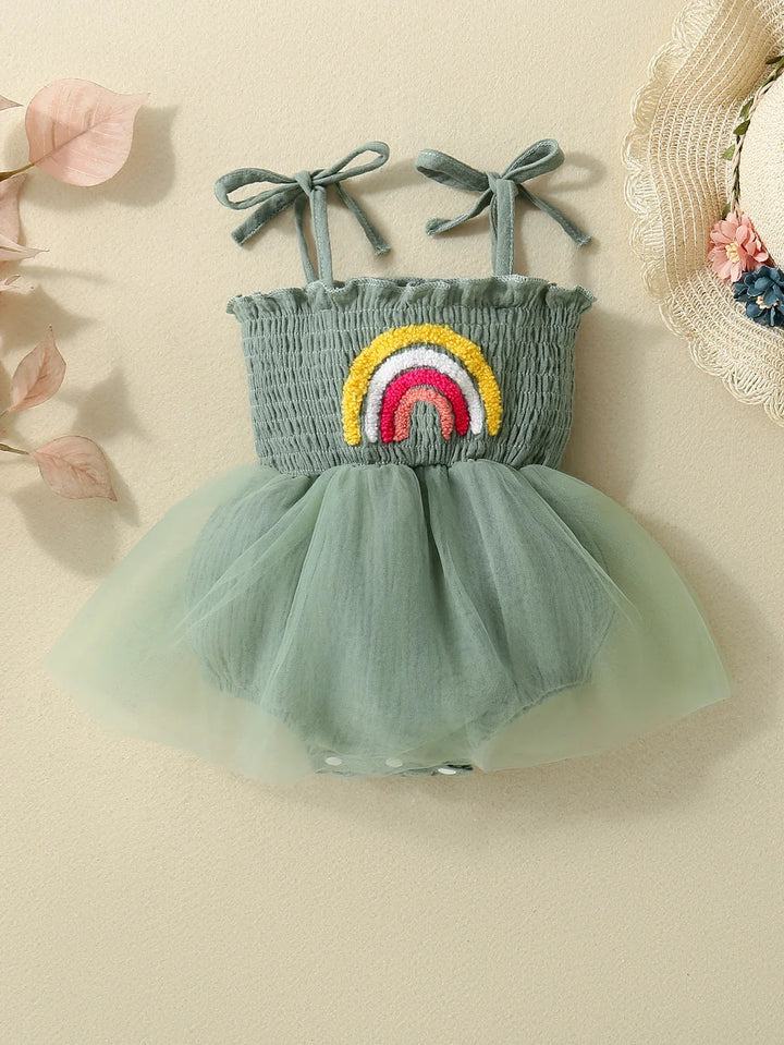 Green baby romper with smocked bodice, tulle skirt, rainbow appliqué, and bow shoulder straps