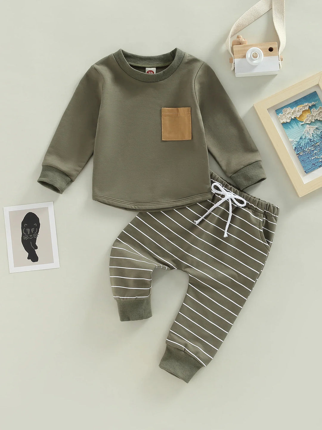 Olive green toddler outfit with long sleeve top featuring a brown pocket and striped pants with white drawstring