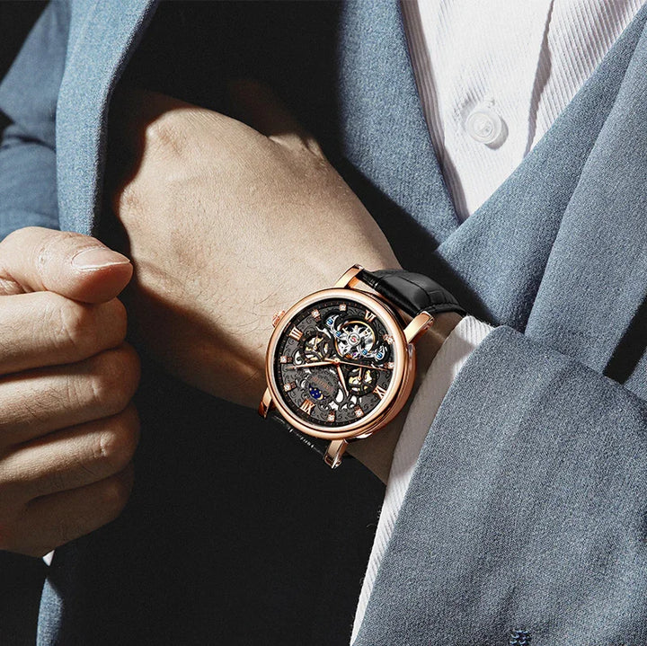 Close-up of a black leather strap skeleton watch with rose gold case worn on wrist with blue suit