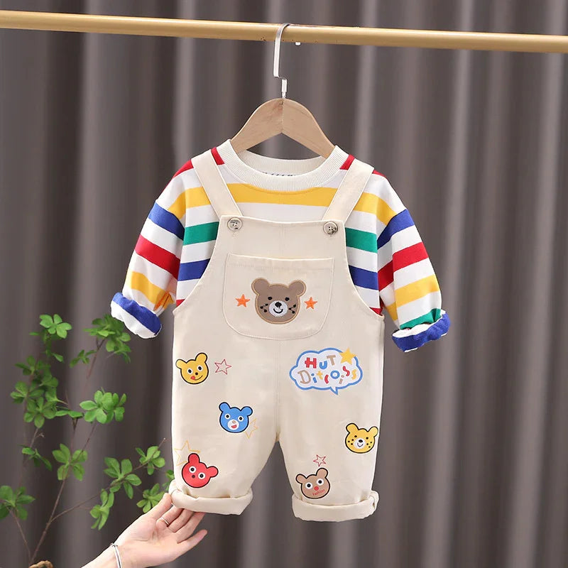 Cute beige toddler overalls with colorful bear patches and striped long-sleeve shirt hanging on wooden hanger