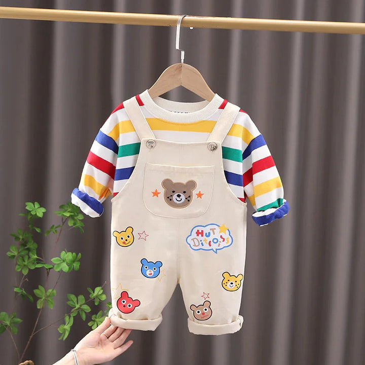 Cute beige toddler overalls with colorful bear patches and striped long-sleeve shirt hanging on wooden hanger