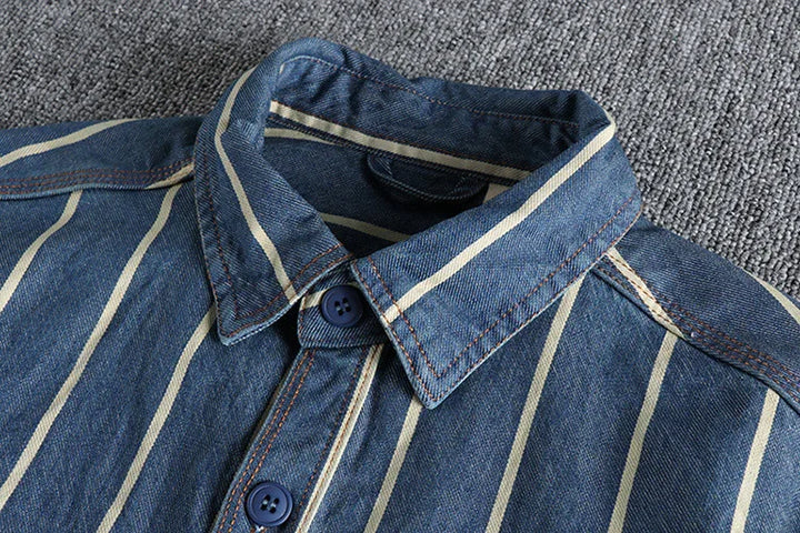 close-up of blue denim shirt with white vertical stripes and blue buttons on gray fabric background