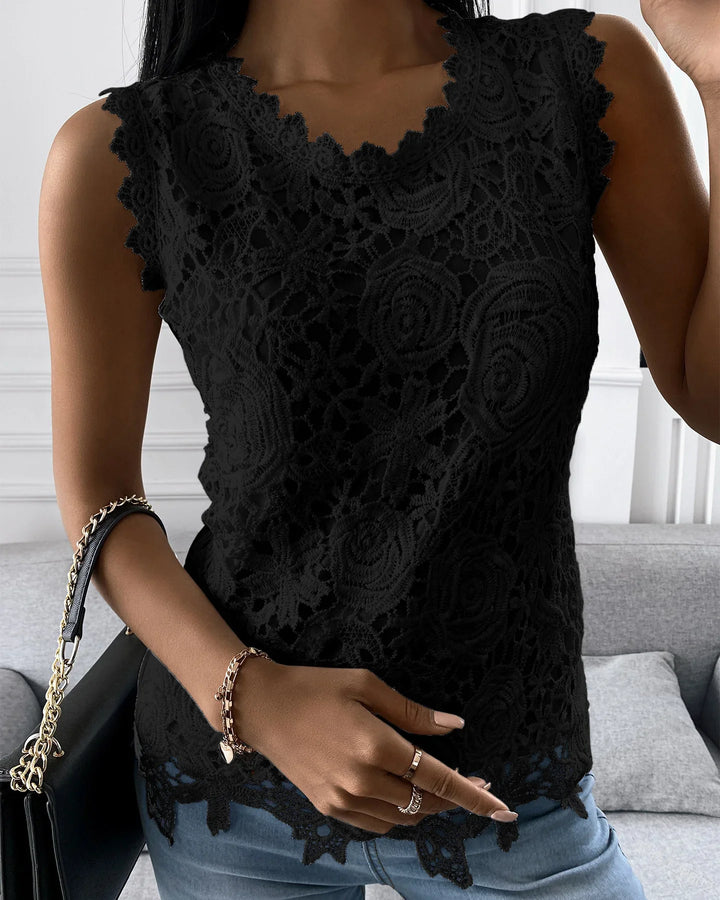 Woman wearing black lace sleeveless top with floral patterns and blue jeans, accessorized with gold bracelets and rings