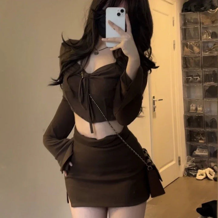 Woman taking mirror selfie in brown long-sleeve crop top and matching mini skirt with crossbody bag in bedroom