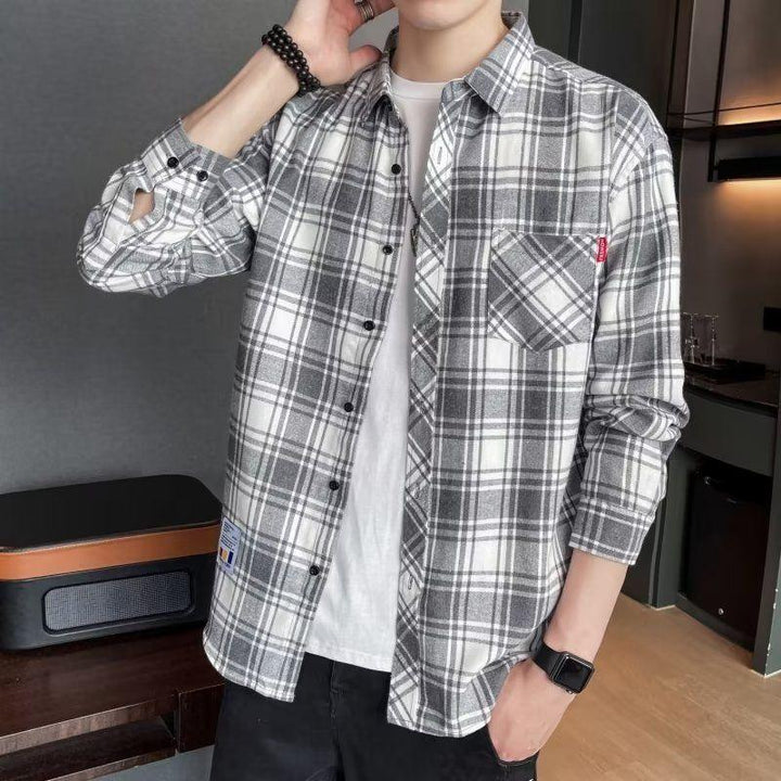 Man wearing a gray and white plaid flannel shirt over a white t-shirt, casual indoor setting