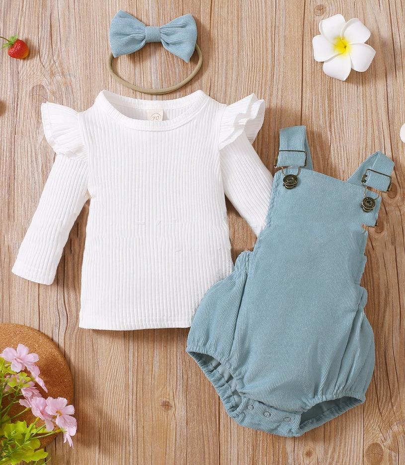 Baby outfit set with white ribbed long-sleeve top, blue romper, and matching blue bow headband on wood