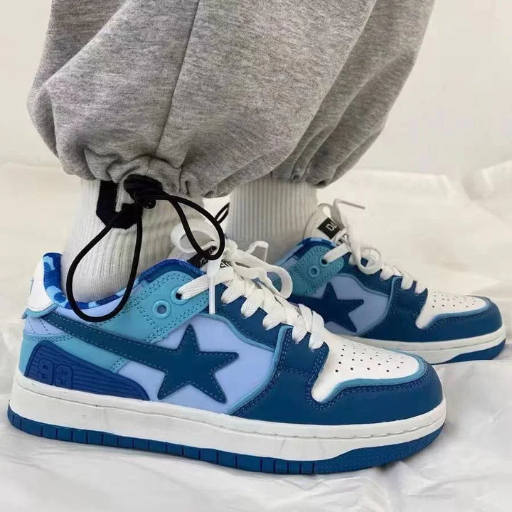 Blue and white low-top sneakers with star logo, worn with white socks and gray joggers