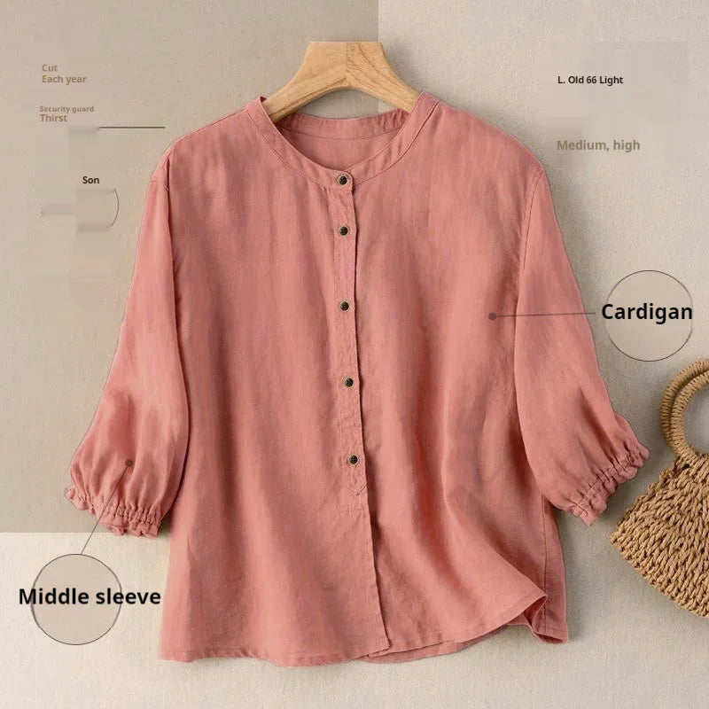 Pink button-up cardigan with middle sleeves on wooden hanger beside woven bag