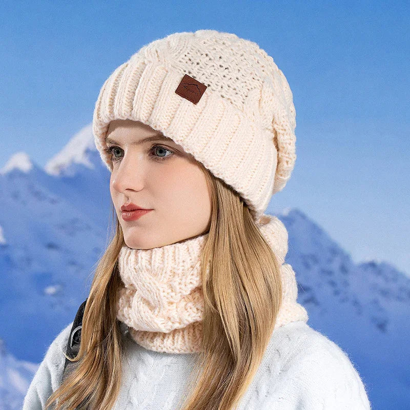 Woman wearing cream knit beanie and matching neck warmer with snowy mountain background