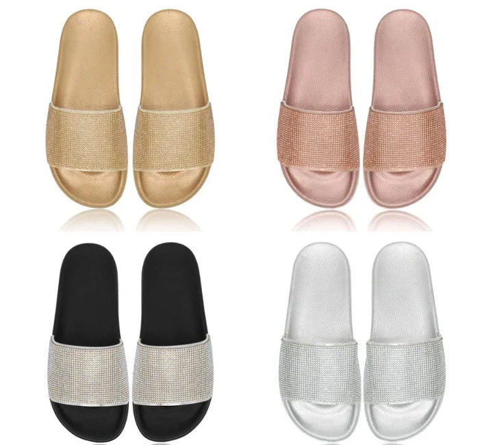 Four pairs of slide sandals in gold, rose gold, black with rhinestones, and silver with rhinestones on white background